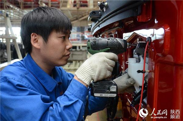 青年工人薛立在安装汽车原配件。张龙 摄影