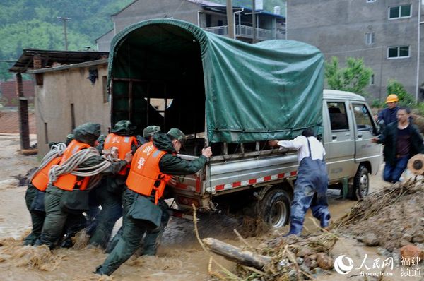 在距离下墘村10多公里处，道路淤泥厚积，武警官兵及当地群众齐心保障道路通行。邓忠卫摄