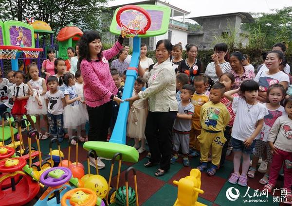 5月29日，在广西融水苗族自治县香粉乡香粉村，一名妇联干部给儿童家园赠送微型篮球架。