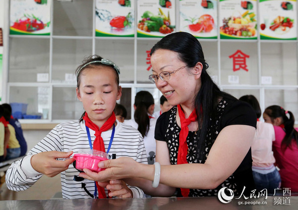 5月31日，在广西柳州市融安县浮石镇东江小学，工作人员在为学生送节日蛋糕