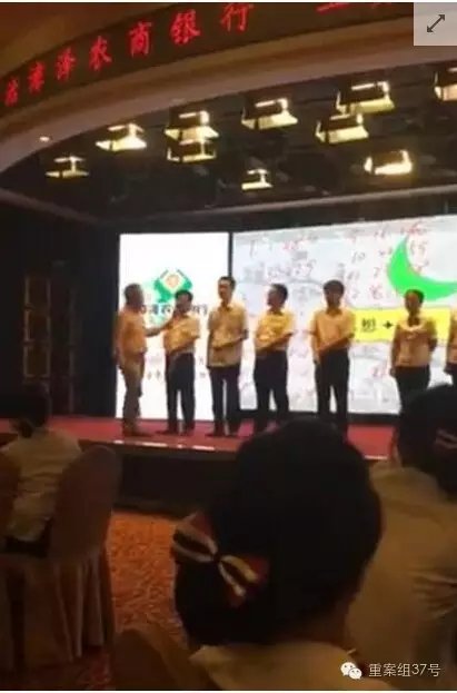 ▲手持长条状木板的中年男子手持话筒,挨个向8人问话。 视频截图