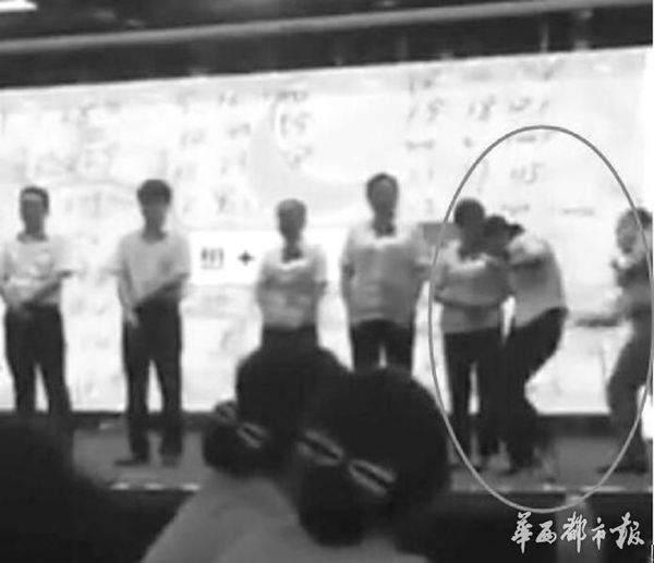 培训师手持木板当众打银行员工。(视频截图)