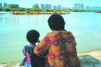 九龙江畔，一位奶奶带着孙女在看龙舟。端午前半个月开始，沿河居住的人们就开始了与水的亲密接触。一条龙舟有时搭载的是一个村所有的精壮汉子。
