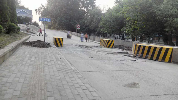 被挪移的限宽架、损毁的路面和乱堆放的渣土。