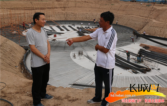 商务局孙坤（左）带病工作，就循环水池项目与施工方沟通。