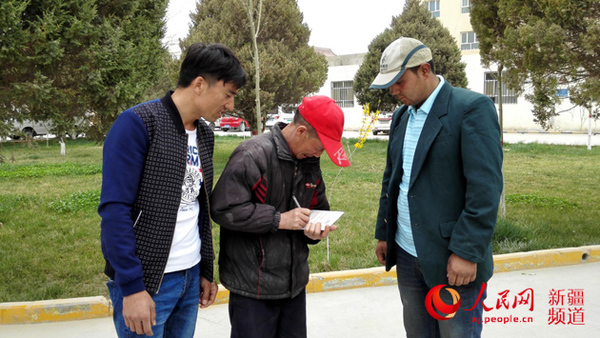 4月3日下午，李金明（中）签收邮局寄来的图尔迪（左）刚办下来的新身份证。记者杨明方摄