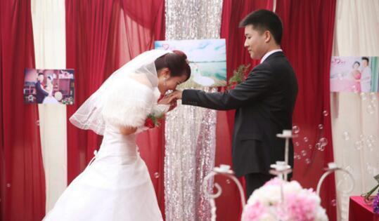 资料图片：2015年2月16日，安徽省滁州市的一场婚礼上，新娘为新郎戴上婚戒，并献上一吻。