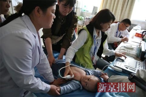 专家在为当地先心病疑似患儿检查。新京报记者 薛珺 摄