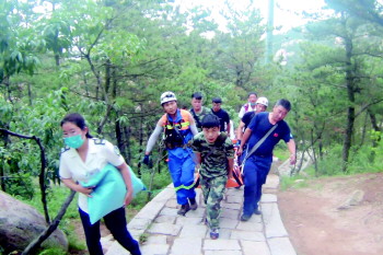 救援人员将小伙抬下山。(视频截图)