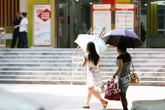 九龙坡区，早上的气温已经十分炎热，市民撑伞出行。记者 石涛 摄