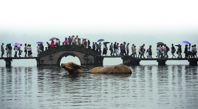 游客行走在杭州西湖涌金桥上。