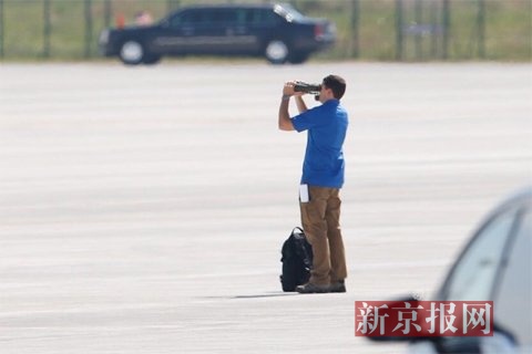 奥巴马离开机场后，一名美国工作人员用高倍望远镜继续在机场观察。