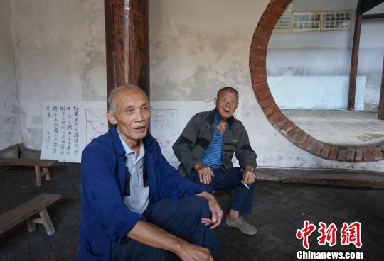 图为文庚有老人（左）在玉溪村祠堂讲述红军故事。　赵琳露　摄