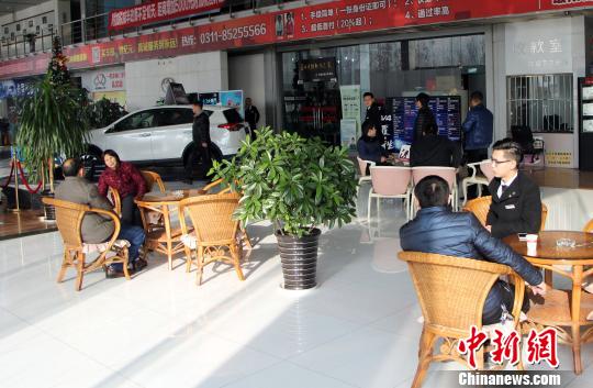 图为4S店看车的顾客与工作人员交谈。　韩冰　摄