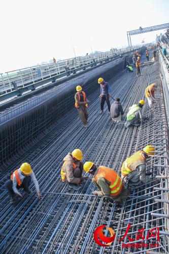 巴基斯坦当地工人在U型梁加工制作基地的巨大模板内捆扎钢筋,该模板从中国引进;(人民网记者 徐伟摄)
