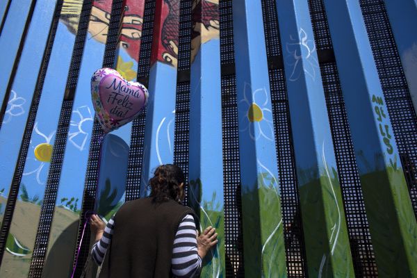 这是在墨西哥蒂华纳拍摄的一名妇女隔着墨美边境栅栏与女儿对话的资料照片。新华社发