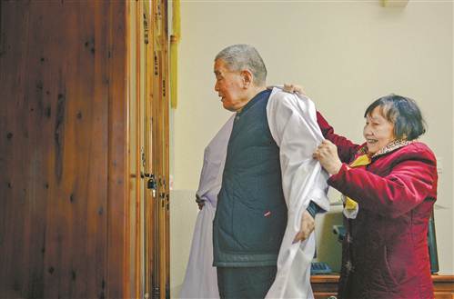 图④段亚亭在老伴的帮助下,脱下白大褂,完成了一天的工作。