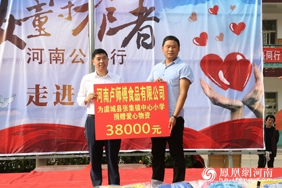 河南卢师傅食品有限公司董事长卢彬（左）向张集镇中心小学捐赠价值三万八千元的爱心物资。