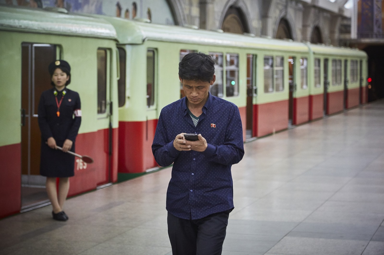 在这个极致之旅 平壤地铁站内,一位男子正在使用安卓手机