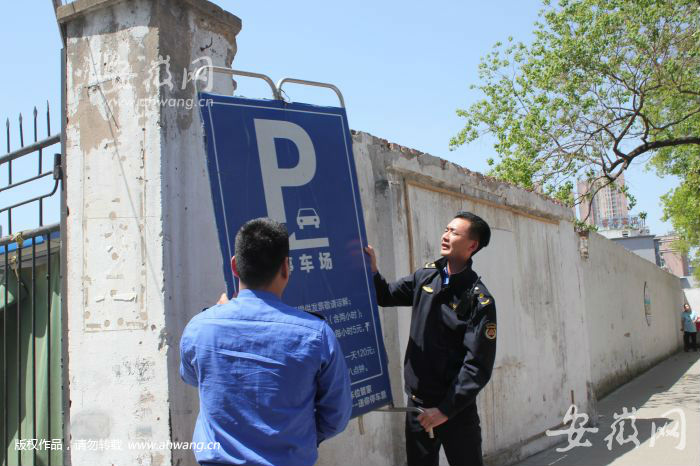 城管人员摘下非法停车场指示牌。