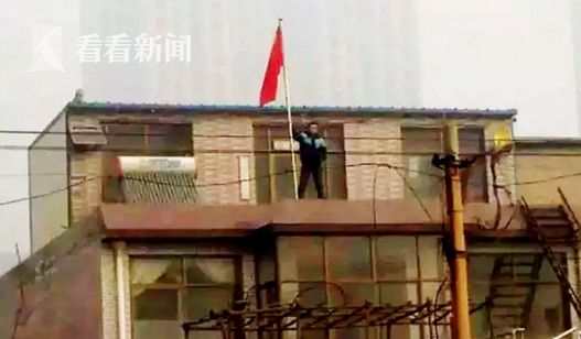 网上流传的贾敬龙家被拆时照片，贾敬龙举着红旗站在楼上。
