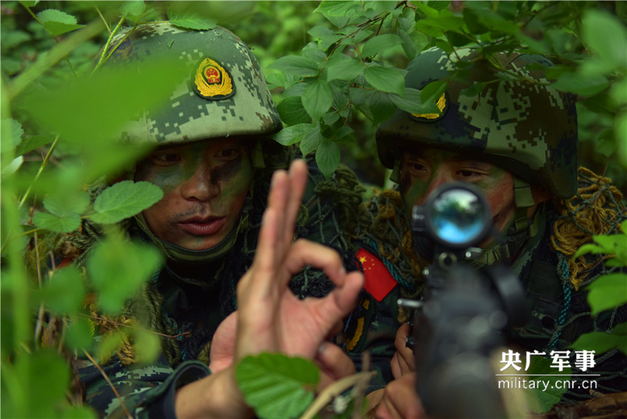 狙击手王孝帅在丛林中给队友杨行行（右）讲解狙击瞄准动作要领。徐伟摄