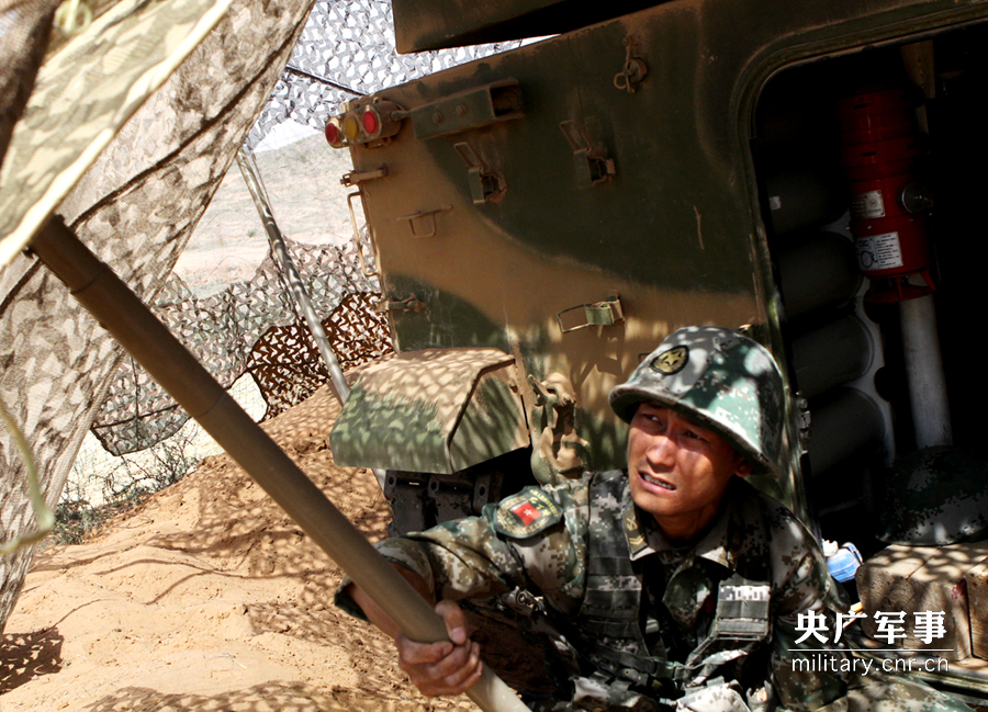 战士对装甲车进行隐蔽伪装