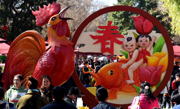 人们在昆明市大观公园的“鸡年迎春”造型前留影。（新华社记者 蔺以光 摄）