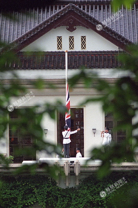 攝影:保羅·拉卡託斯1997年6月30日,一群菲傭坐在印有董建華畫像的