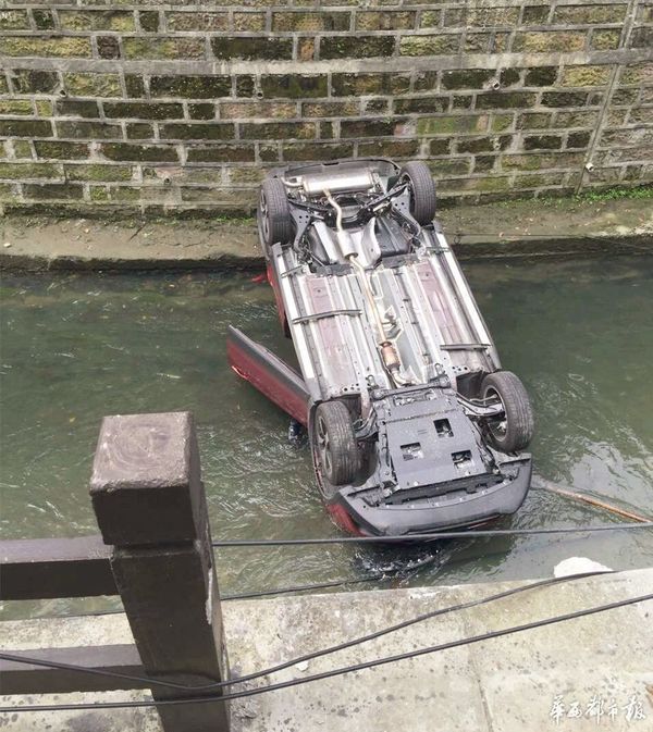 一辆红色轿车在倒车时,劲儿使太猛,直接把车倒进了河里,翻了个底朝天