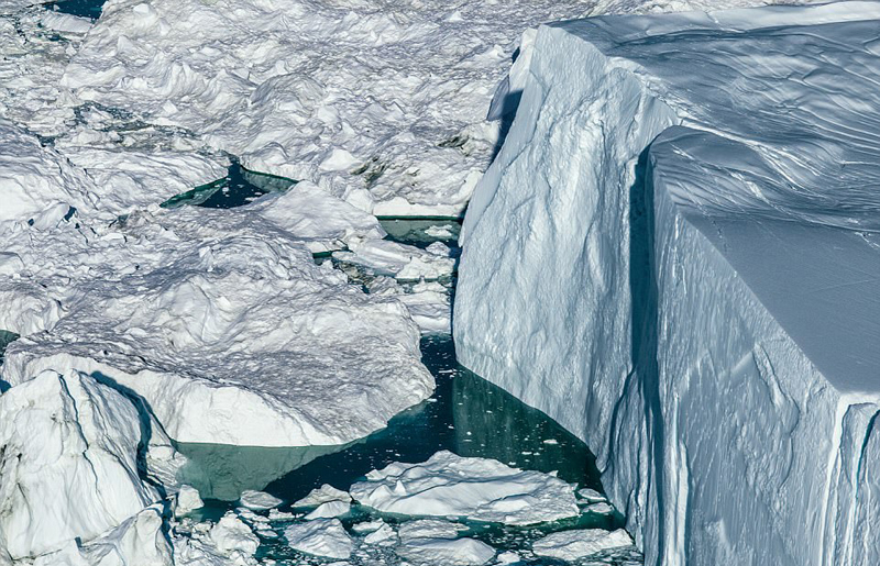 在一张照片中,厚厚的冰层裂开了一条大缝,冰块正逐渐融化并没入水中.